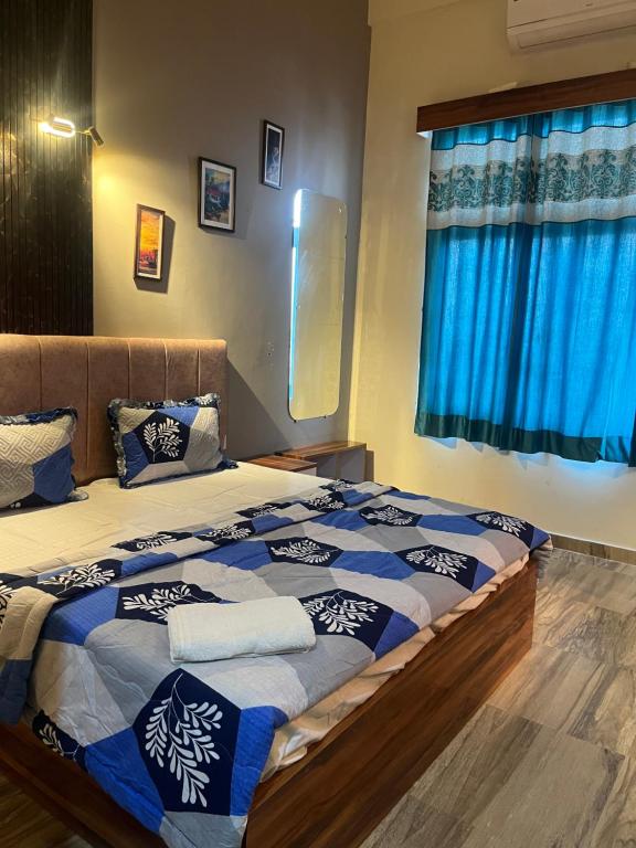 a bedroom with a large bed with blue curtains at Luxury apartment near expo in Greater Noida