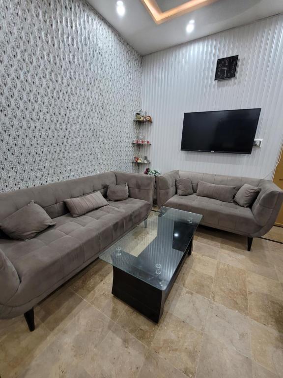 Harrys Guest House في Gujrānwāla: غرفة معيشة مع أريكة وتلفزيون بشاشة مسطحة