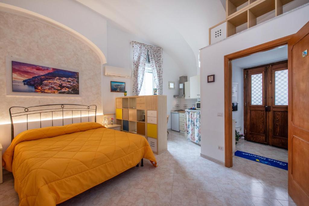 a bedroom with a yellow bed and a kitchen at Casa Hermes in Atrani