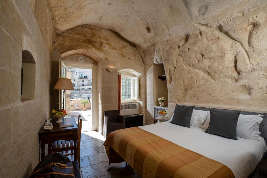a bedroom with a bed in a stone wall at Locanda Di San Martino Hotel & Thermae Romanae in Matera