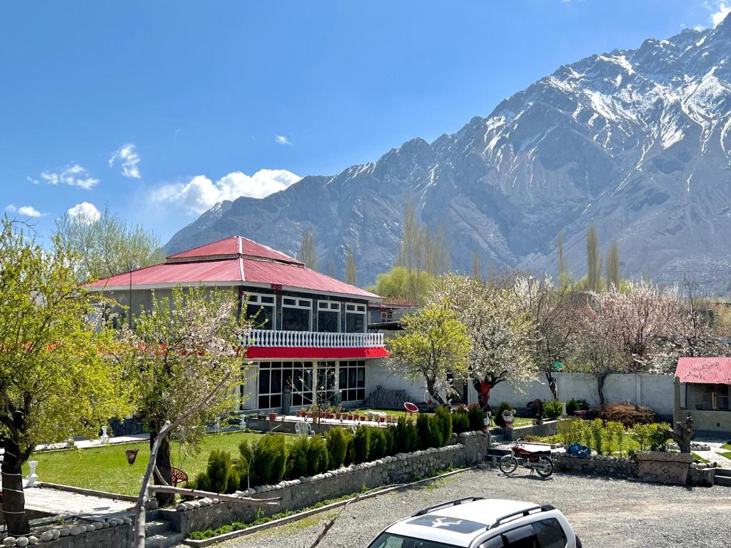 a building with a car parked in front of it with a mountain at Hotel Travel Lodge in Skardu