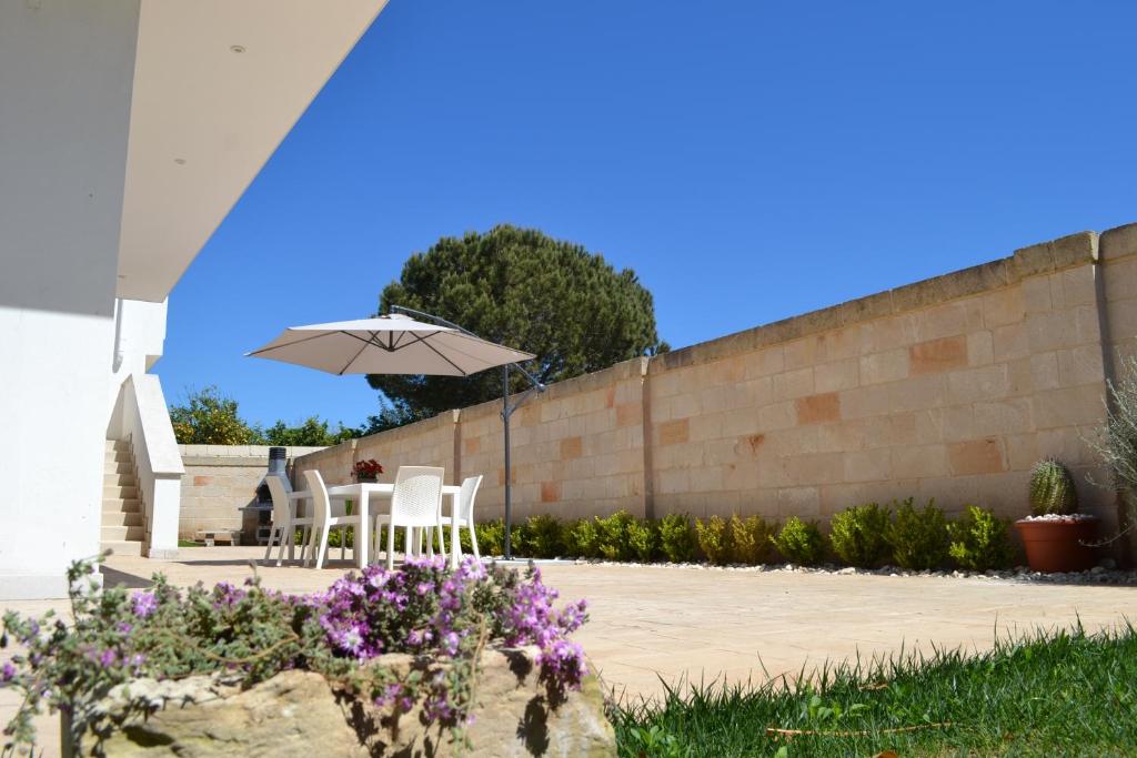 un patio con due sedie bianche e un ombrellone di Villa Serena a Bagnolo del Salento