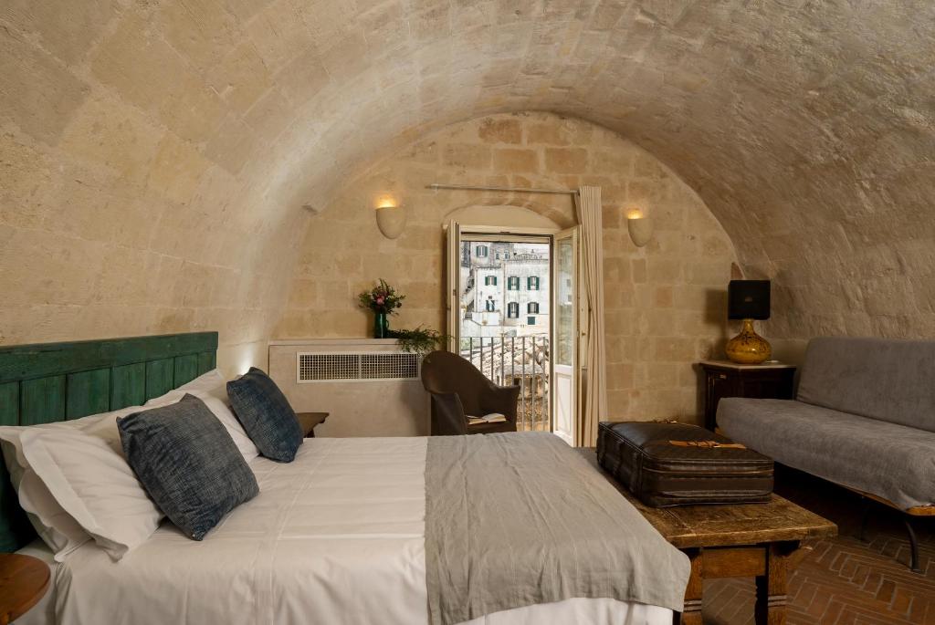 a bedroom with a bed and a couch and a window at Locanda Di San Martino Hotel & Thermae Romanae in Matera