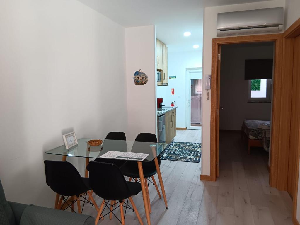 a dining room and kitchen with a glass table and chairs at Casa Bateira in Figueira da Foz
