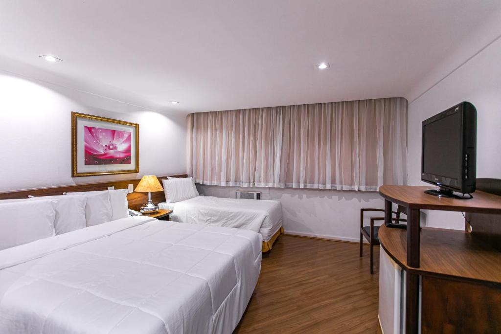 a hotel room with two beds and a flat screen tv at Hotel Dan Inn Curitiba Centro in Curitiba