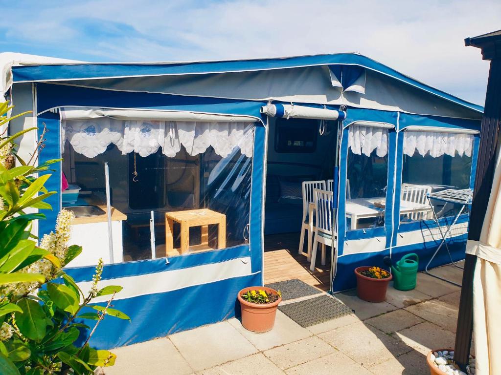 eine blaue Hütte mit einem Tisch und Stühlen in der Unterkunft Luxoriöser Wohnwagen 400 Meter vom Meer in Grömitz. in Lenste