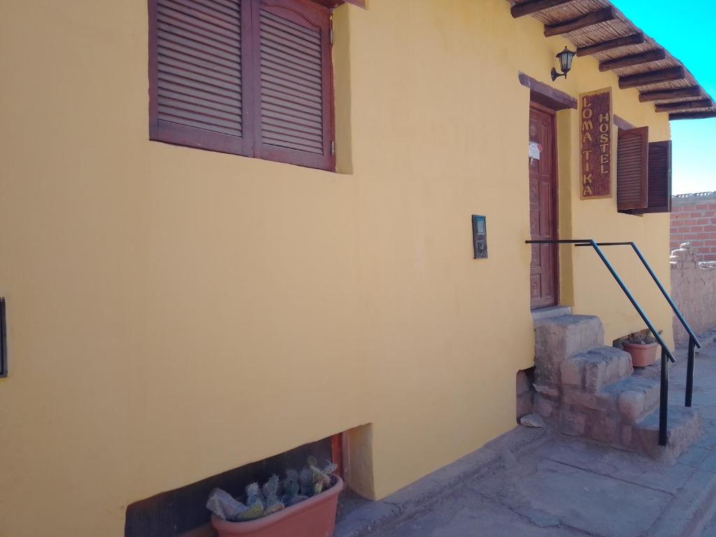 een zijdelings uitzicht op een huis met een deur en een veranda bij Loma Tika - Tilcara Hostel in Tilcara