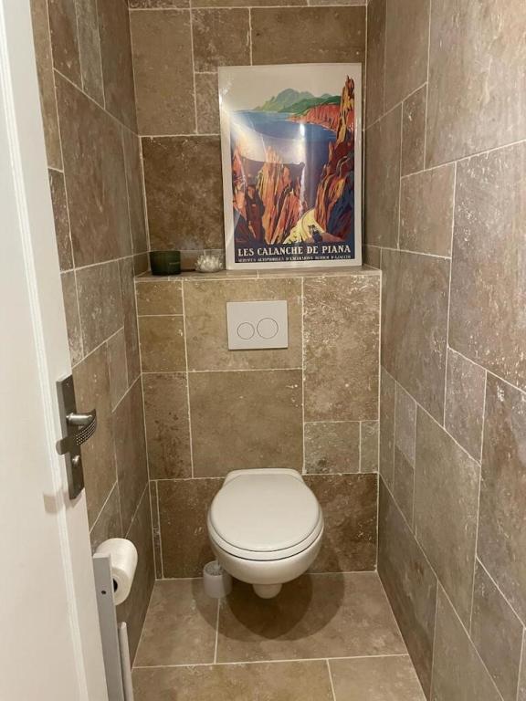 a bathroom with a toilet and a painting on the wall at Villa Turquoise Sagone in Sagone