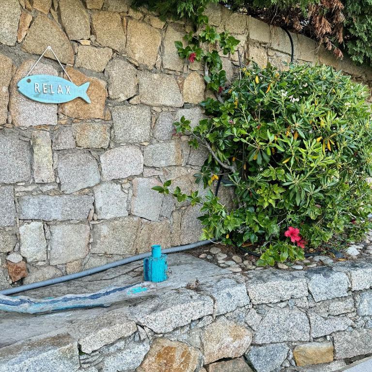 a stone wall with a bush and a sign on it at Villa Turquoise Sagone in Sagone