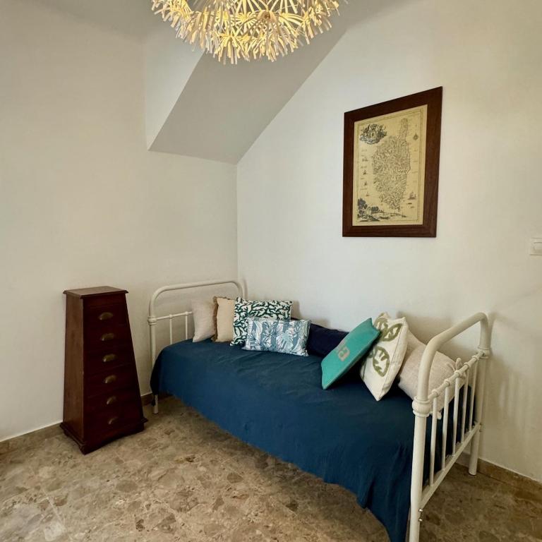 a bedroom with a bed with blue sheets and a chandelier at Villa Turquoise Sagone in Sagone