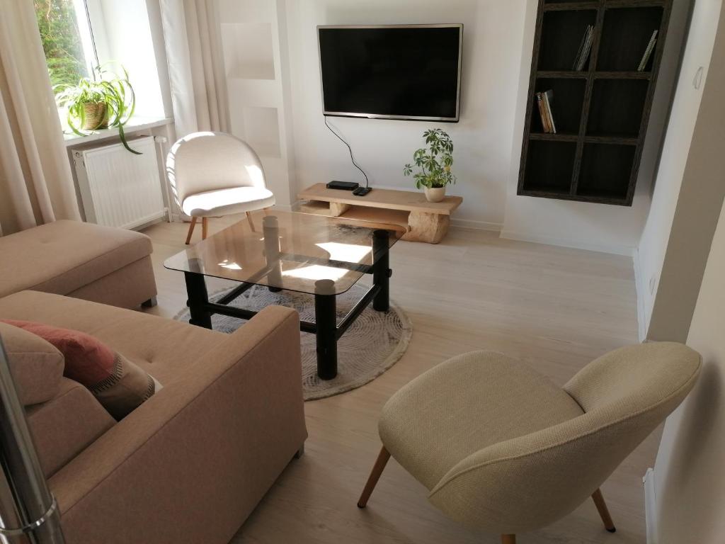 ein Wohnzimmer mit einem Sofa, einem Tisch und einem TV in der Unterkunft Apartament u Przewodnika Sudeckiego in Duszniki-Zdrój
