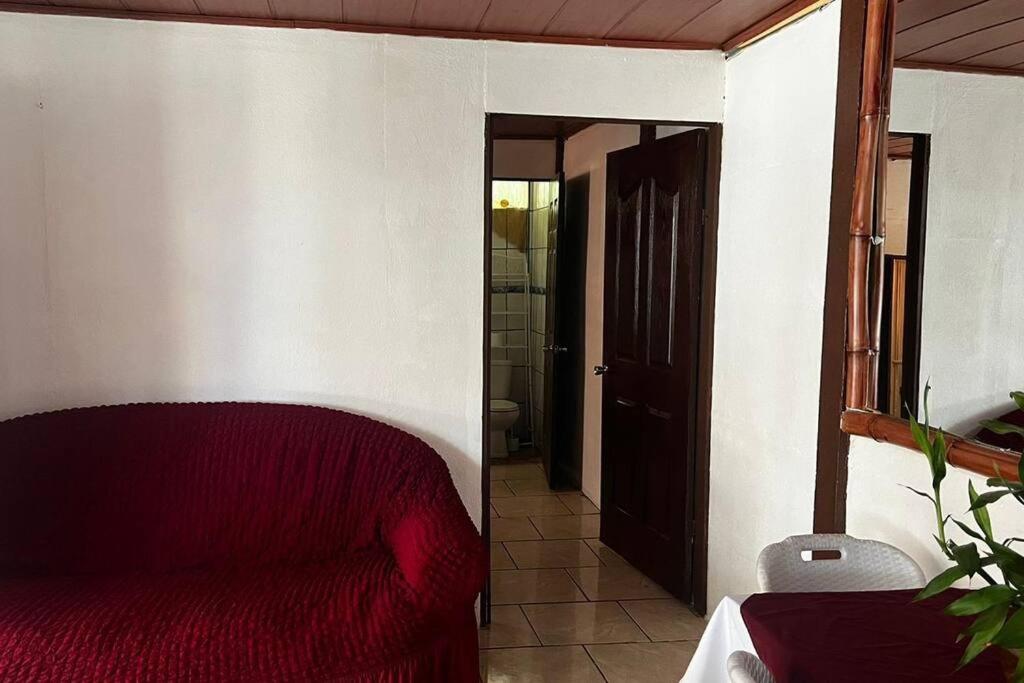 a bedroom with a red bed and a bathroom at Luna Turquesa in Golfito