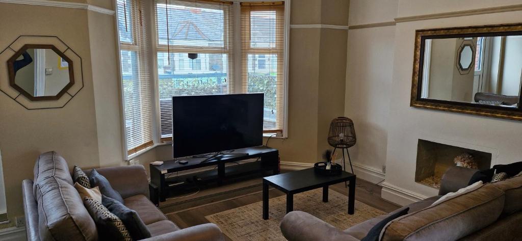 a living room with two couches and a flat screen tv at Large Three Bedroom Apartment with Roof Terrace Near City Centre in Cardiff