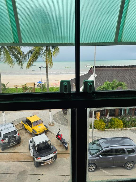 una ventana con vistas a los coches y a la playa en Pousada Gale Orla, en Maragogi