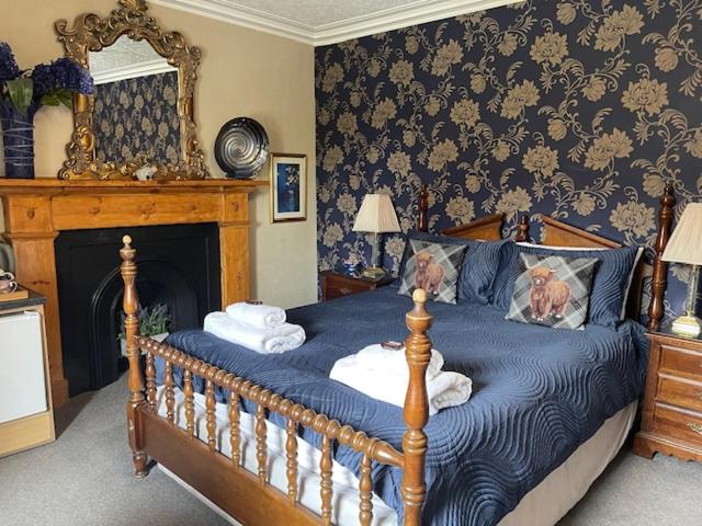 a bedroom with a bed with blue sheets and a fireplace at Dionard Guest House in Inverness