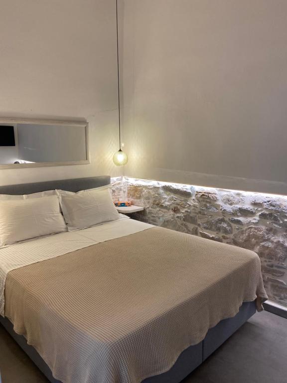 1 dormitorio con 1 cama y una pared con rocas en AVALON Luxury Suites, en Ermoupoli