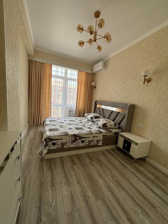 um quarto com uma cama e uma grande janela em Апартаменты CITY PARK em Aktau