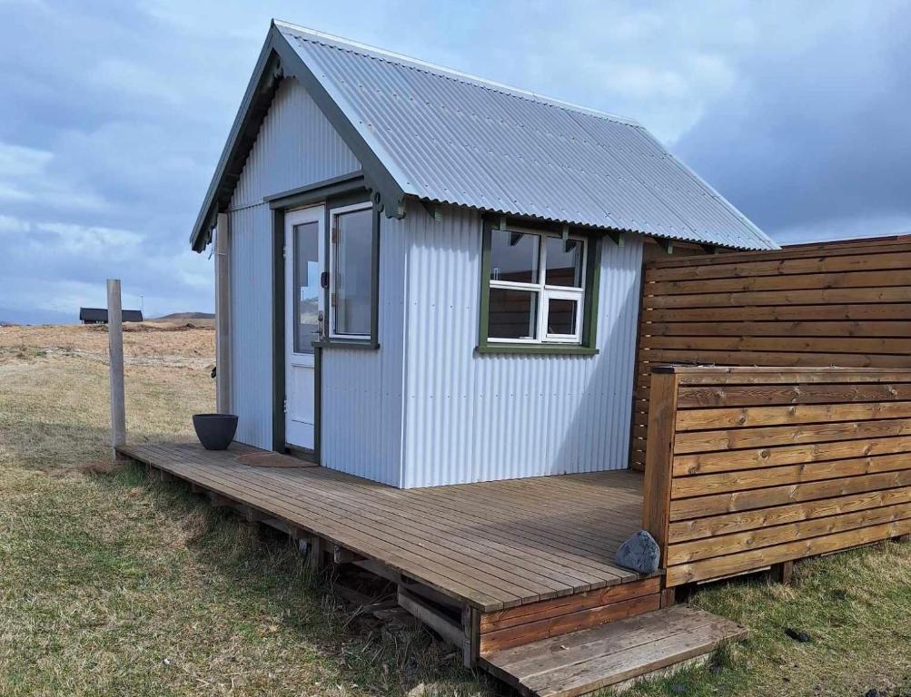 a tiny house on a wooden deck in a field at Ofanleiti Cottages in Vestmannaeyjar