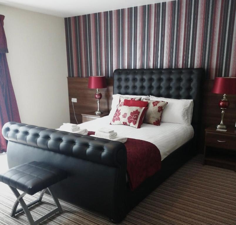 a bedroom with a large bed with a leather headboard at The Hedges Hotel in Stranocum
