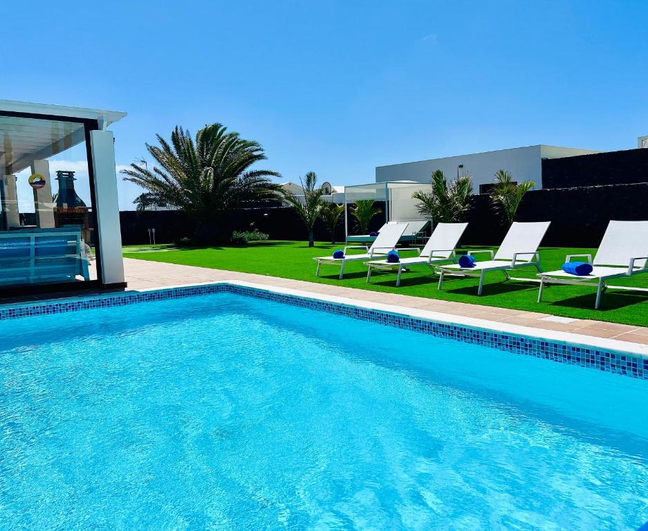 een zwembad met ligstoelen en een huis bij Villa Sunset Zafiro in Playa Blanca