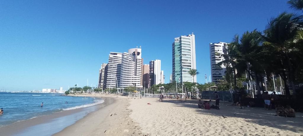 une plage de sable avec de grands bâtiments en arrière-plan dans l'établissement Kitnet, à Fortaleza