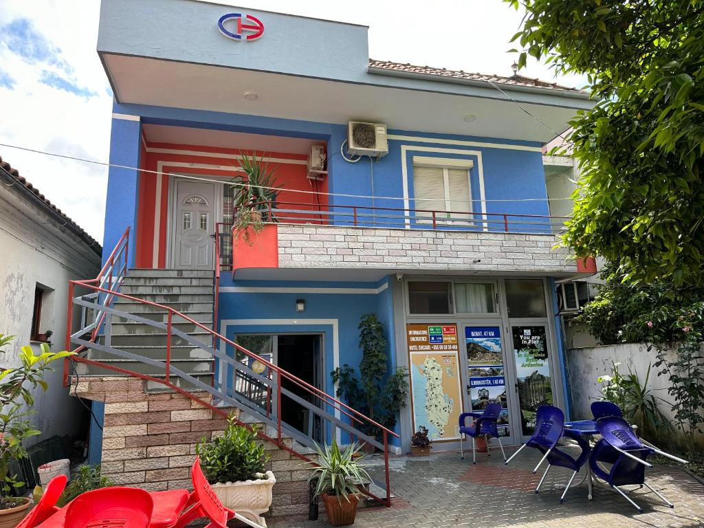 a blue building with red and blue chairs in front of it at Chicago hotel in Fier