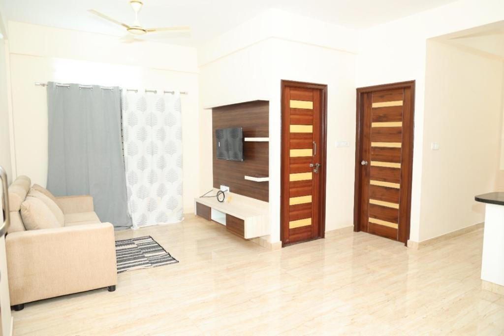 a living room with a couch and wooden doors at HSR Parkside by Newstays in Bangalore