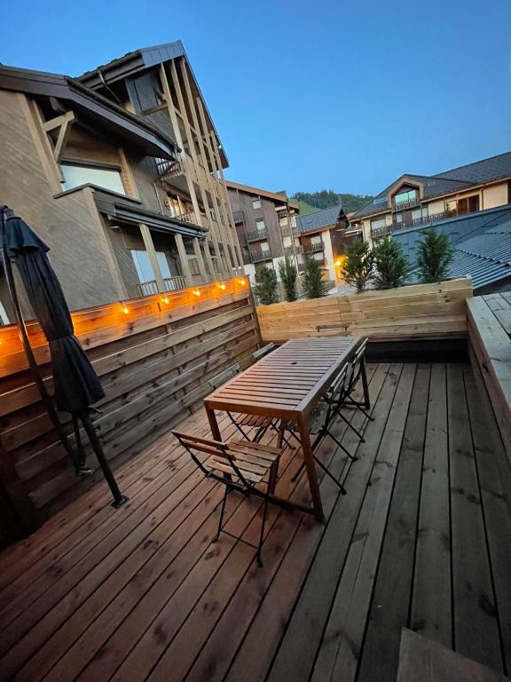 une terrasse en bois avec une table et des chaises dessus dans l'établissement Duplex les Myrtilles LES CARROZ centre station, aux Carroz d'Arâches
