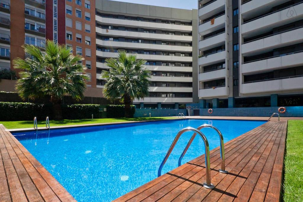 a large blue swimming pool with buildings in the background at Apartment familiar in Barcelona