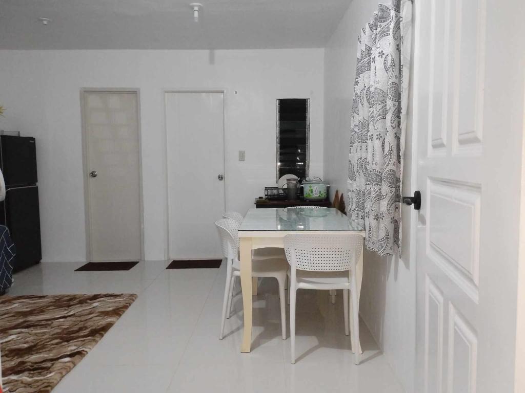 a white kitchen with a table and white chairs at tadzmahal home in Pagadian