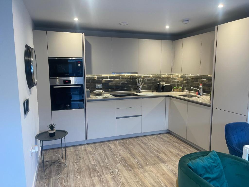 a kitchen with white cabinets and a blue chair at Manchester City Center Apartment in Manchester