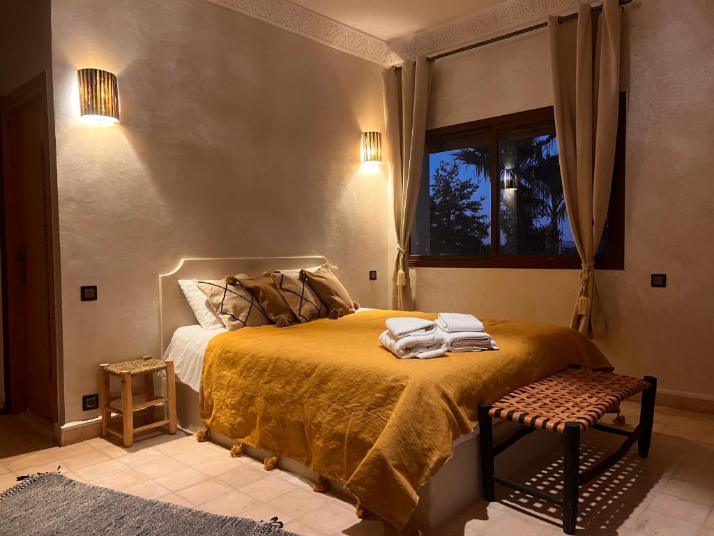 a bedroom with a bed with a yellow blanket and a window at Villa Dar Hadjar in Marrakesh