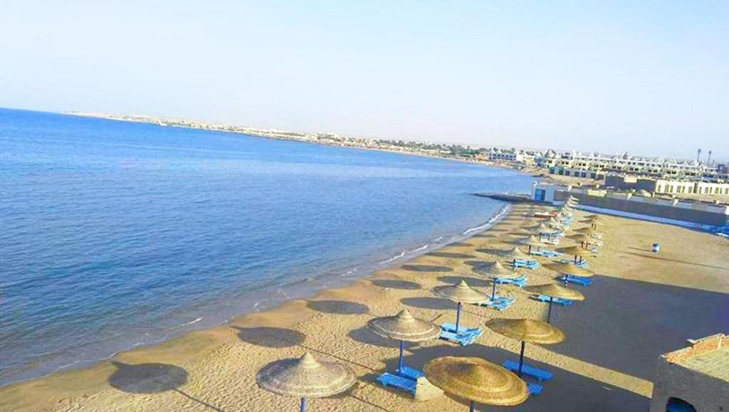 a beach with a bunch of umbrellas and the water at Cecelia Hotel Suites Hurghada in Hurghada