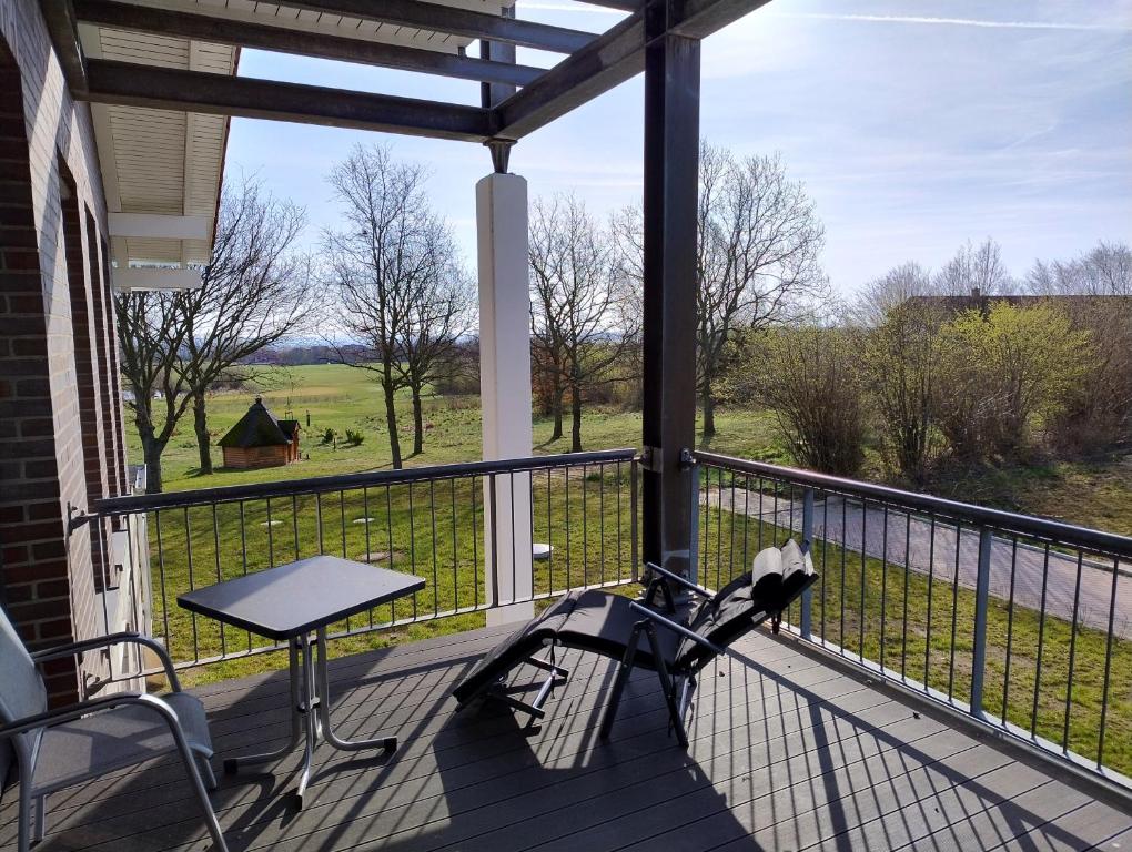 a balcony with a table and chairs and a view of a field at Ostseegolf - Ferienappartement in Hohen Wieschendorf