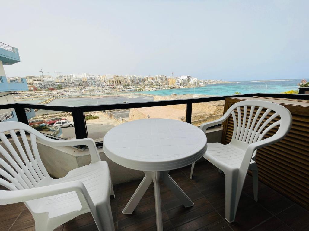 un tavolo bianco e sedie su un balcone con vista sulla spiaggia di Salina Seaview Retreat a Naxxar