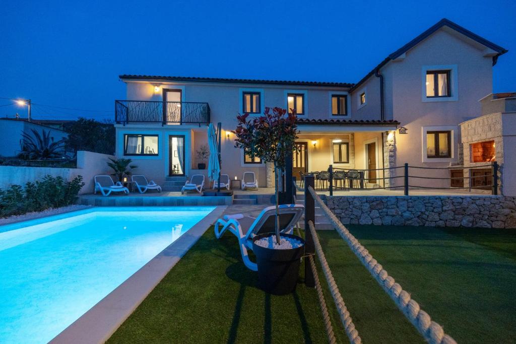 a villa with a swimming pool in front of a house at Villa Fran, Krk in Sveti Vid-Miholjice