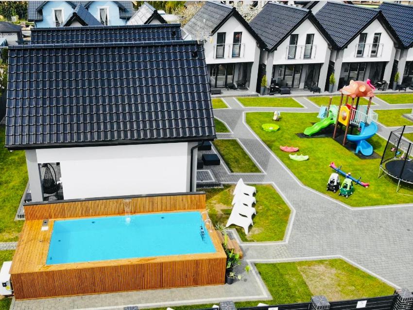 un modelo de patio trasero con piscina y parque infantil en Domki Nord Breeze z podgrzewanym basenem en Władysławowo