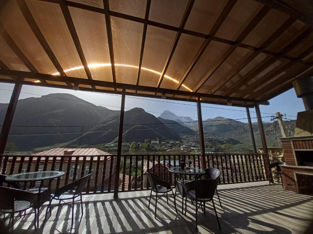 a balcony with tables and chairs and a view of mountains at Come & Rest in Kazbegi