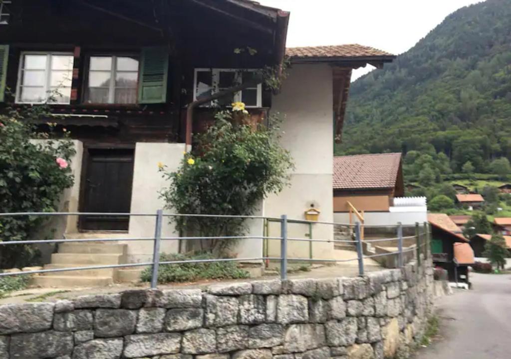 een huis met een stenen muur naast een straat bij Holiday Apartment in Swiss Alps in Gsteigwiler