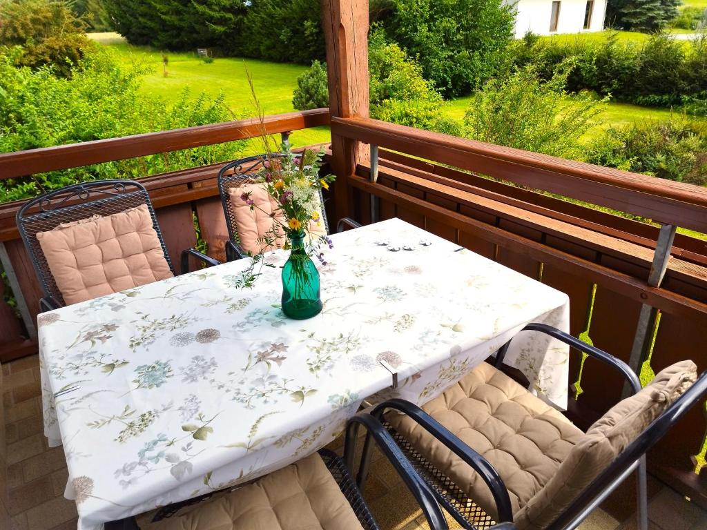 a table and chairs on a balcony with a vase on it at Nassfeld and Lake Apartment in Hermagor