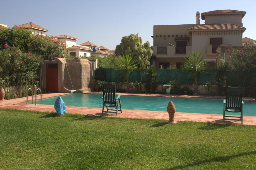 a swimming pool with three chairs in a yard at Marinazur in Saidia 