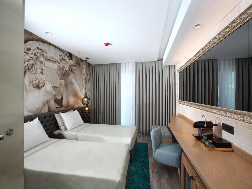 ボドルム・シティにあるEskiceshme Bodrum Marinaのベッド2台とデスクが備わるホテルルームです。