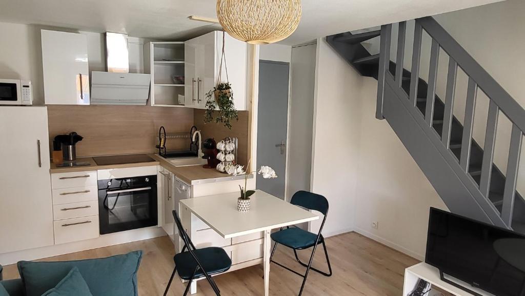 uma pequena cozinha com uma mesa e cadeiras e uma escadaria em Les bastides de la plage-400 m de la plage em Le Grau-du-Roi