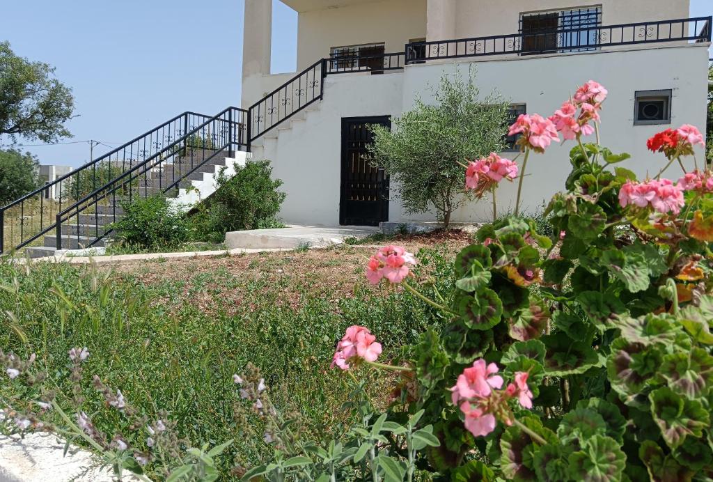 una casa con flores rosas delante de ella en Rousan House, en Um Qeis