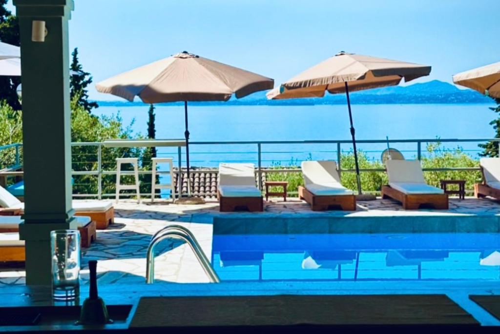 a swimming pool with chairs and umbrellas at Hotel Barbati Sea View B&B in Barbati