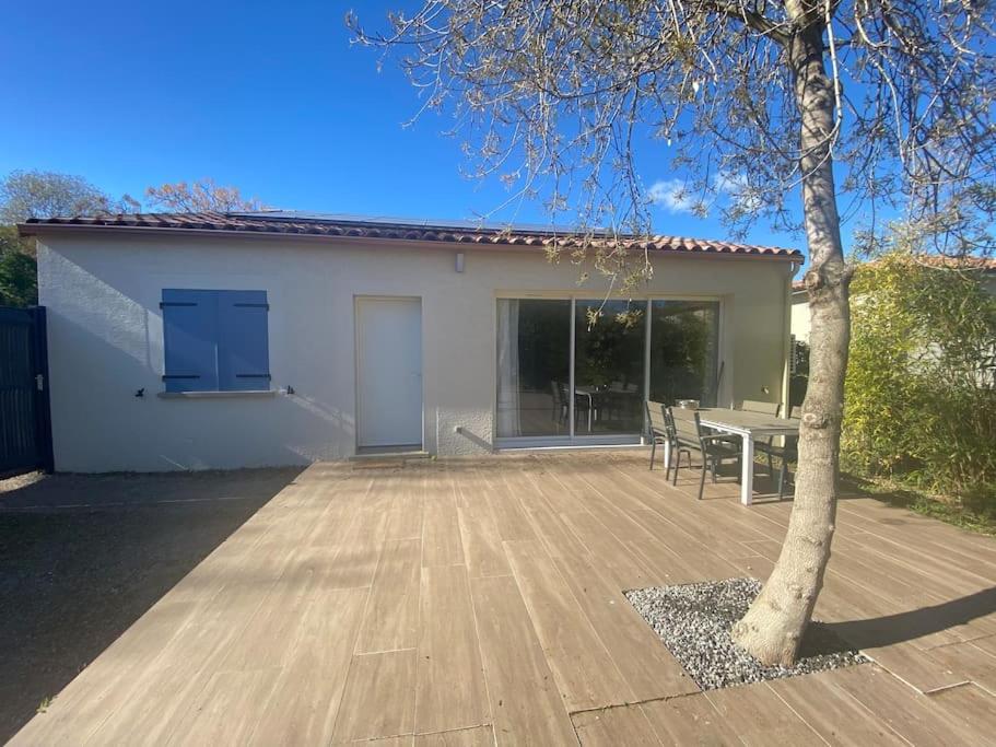 une terrasse avec une table et un arbre en face d'une maison dans l'établissement Maison moderne plain pied, à Saussan