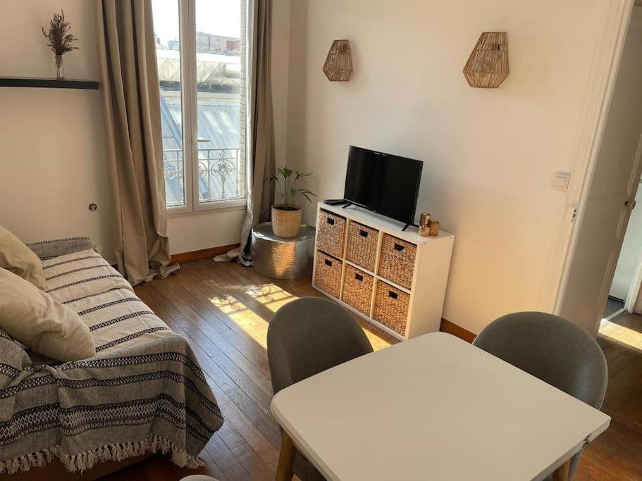 un salon avec une télévision, une table et des chaises dans l'établissement Charmant studio aux portes de Paris, à Saint-Ouen