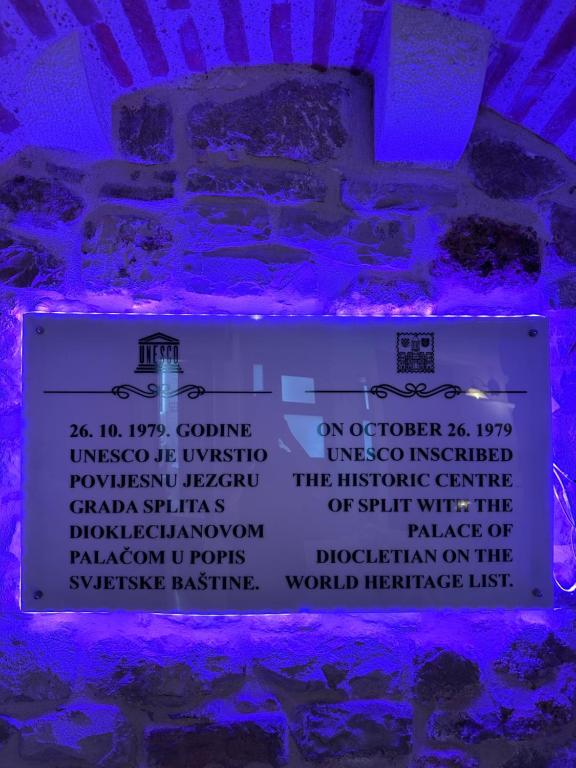 a sign in front of a brick wall with purple lights at Diocletian Wine studio apartment in Split