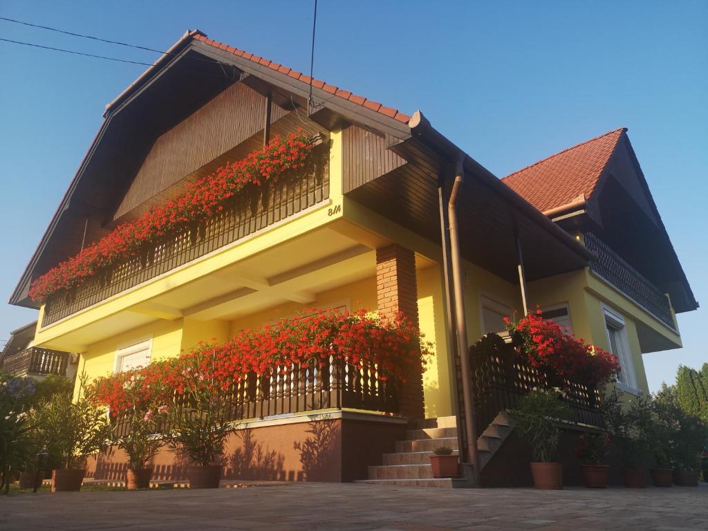 ein Haus mit roten Blumen auf dem Balkon in der Unterkunft Zsuzsi Vendégház in Zalaegerszeg