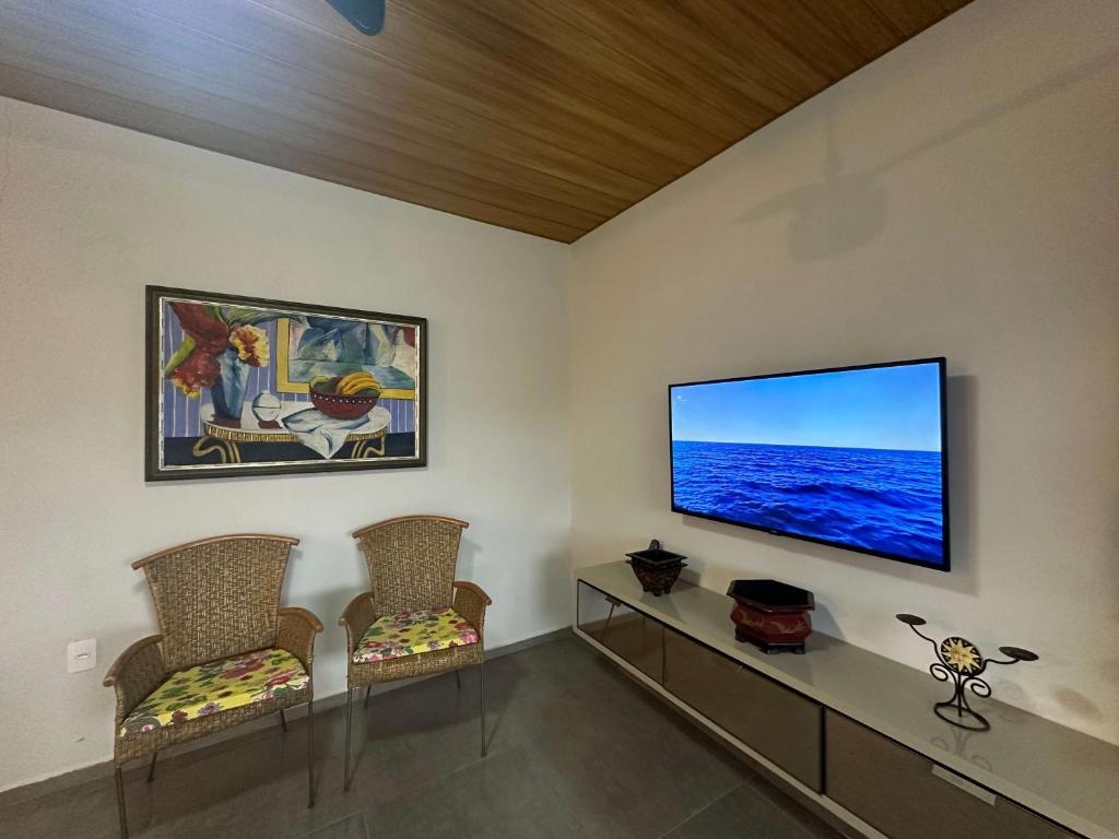 ein Wohnzimmer mit 2 Stühlen und einem Flachbild-TV in der Unterkunft Arara Azul in Florianópolis